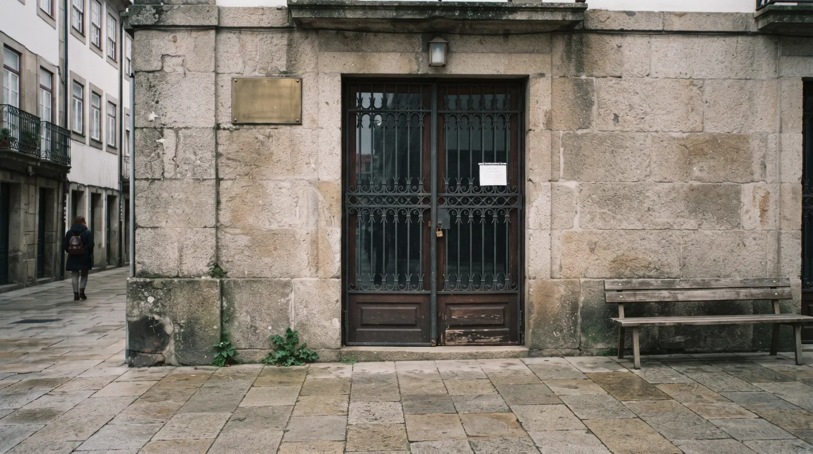 The shuttered iron gates of the Bolhão market on Rua Formosa at 09:30 on a Sunday morning, a few visitors reading the sign — what is closed in Porto on Sunday and Monday