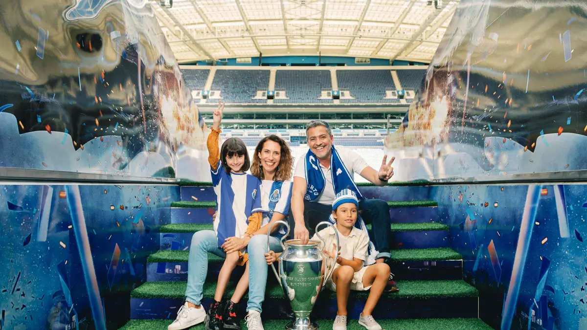 A family posing with a trophy in the stands of the Estádio do Dragão on the FC Porto stadium tour