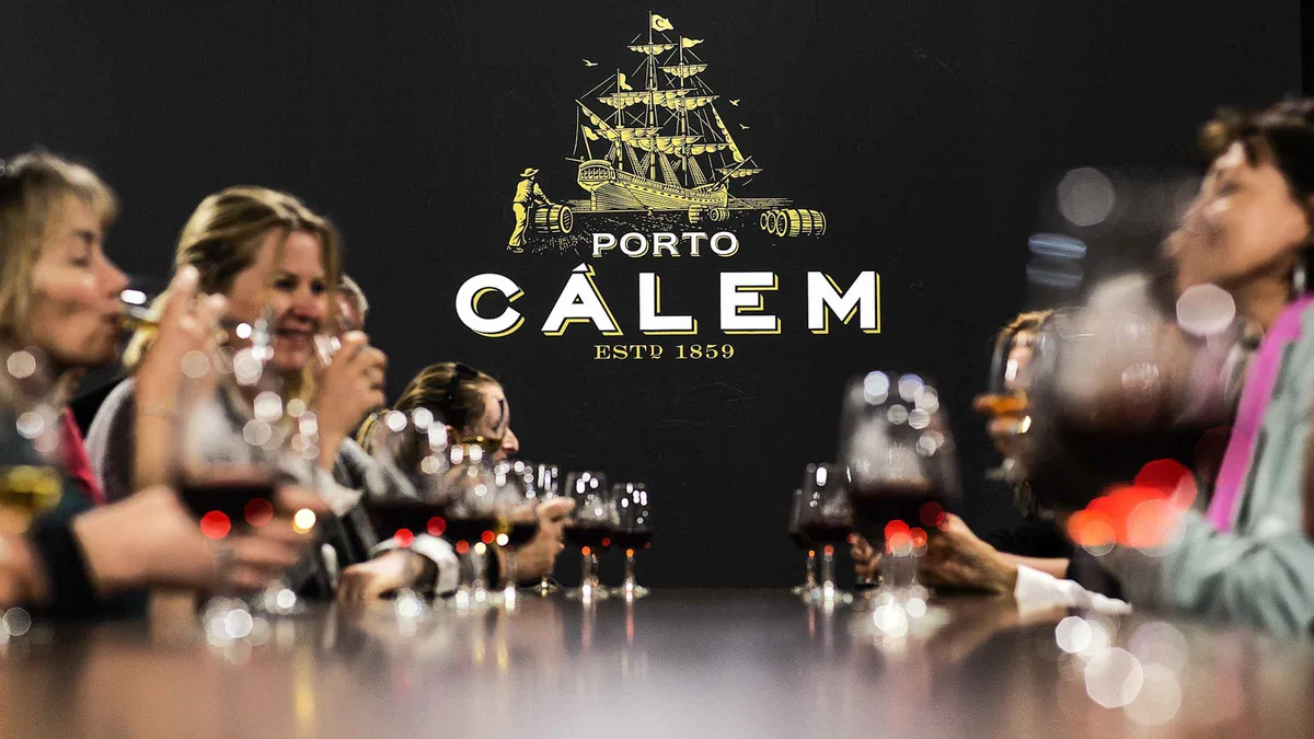 Guests raising glasses of port under the Cálem sign at the Gaia cellar in Porto