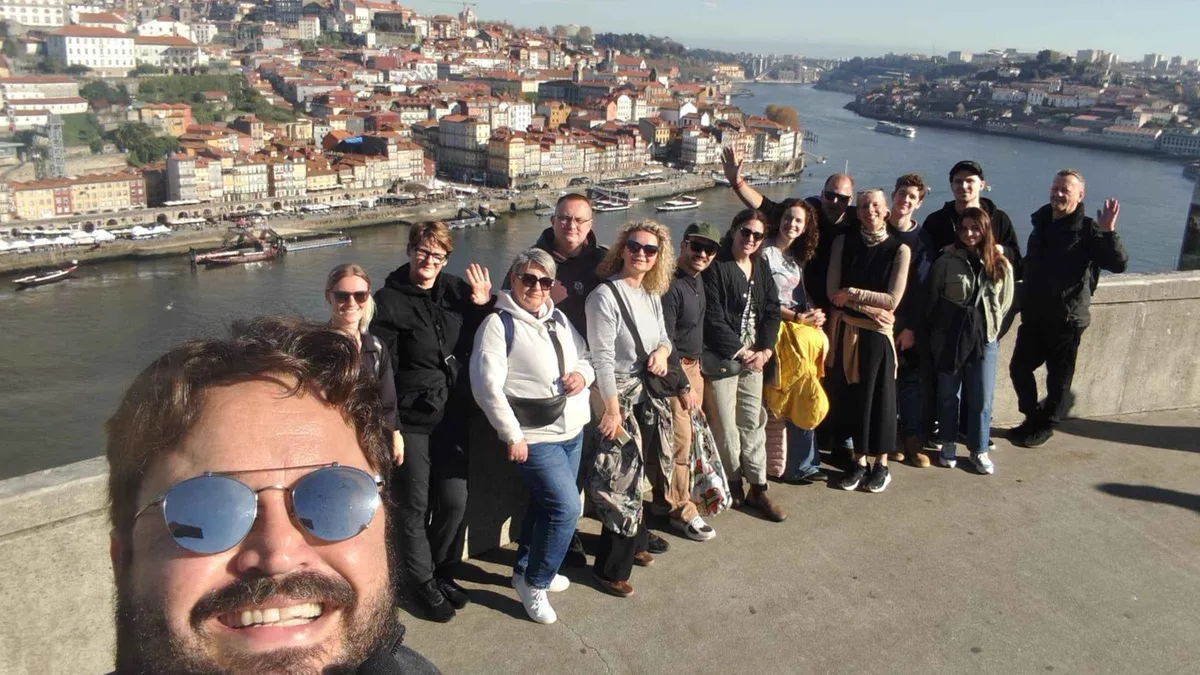 A guide with a walking-tour group on a viewpoint above the Douro and Ribeira in Porto