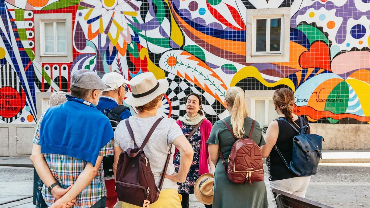 A small walking-tour group in front of a colourful tiled mural in Porto