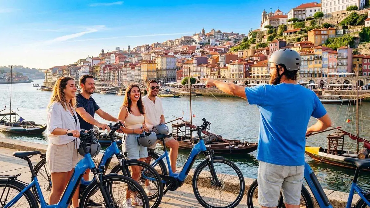 A guide in a helmet with an e-bike group on the Gaia quay opposite Ribeira in Porto