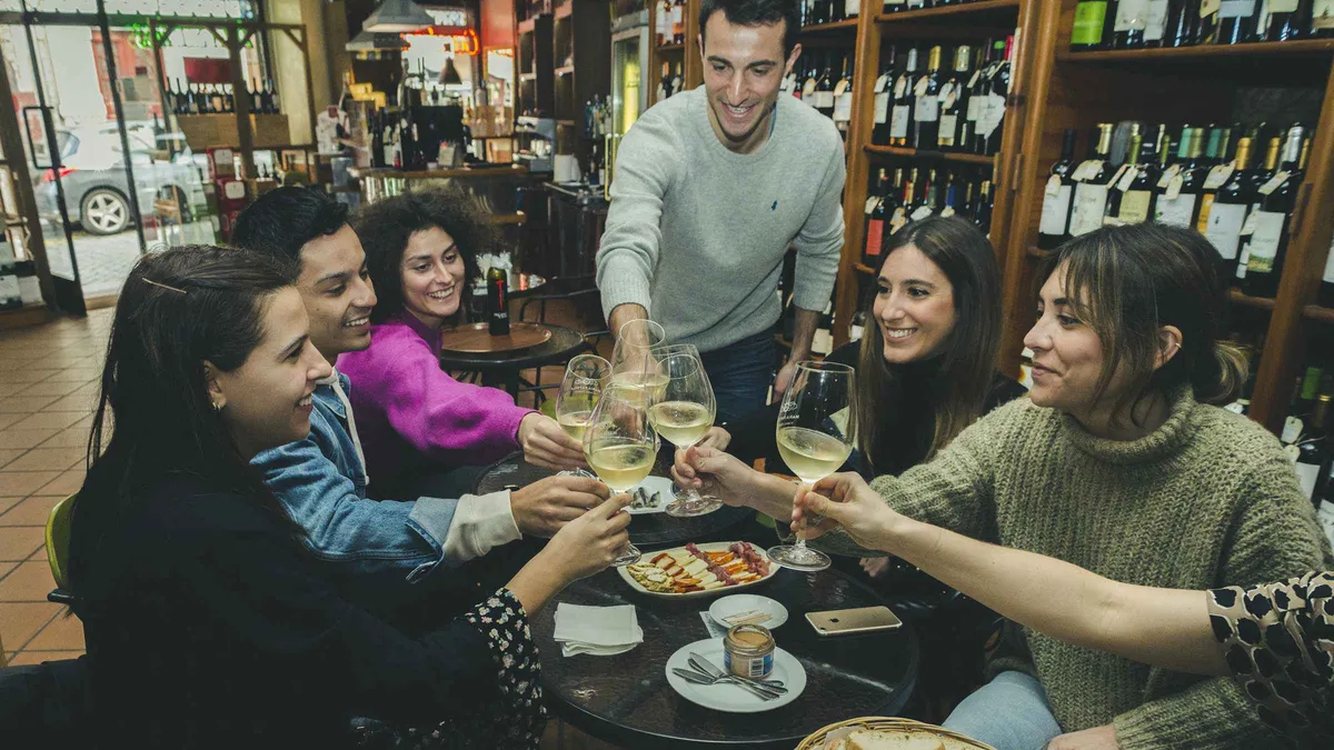 Friends clinking wine glasses over petiscos in a Porto tavern