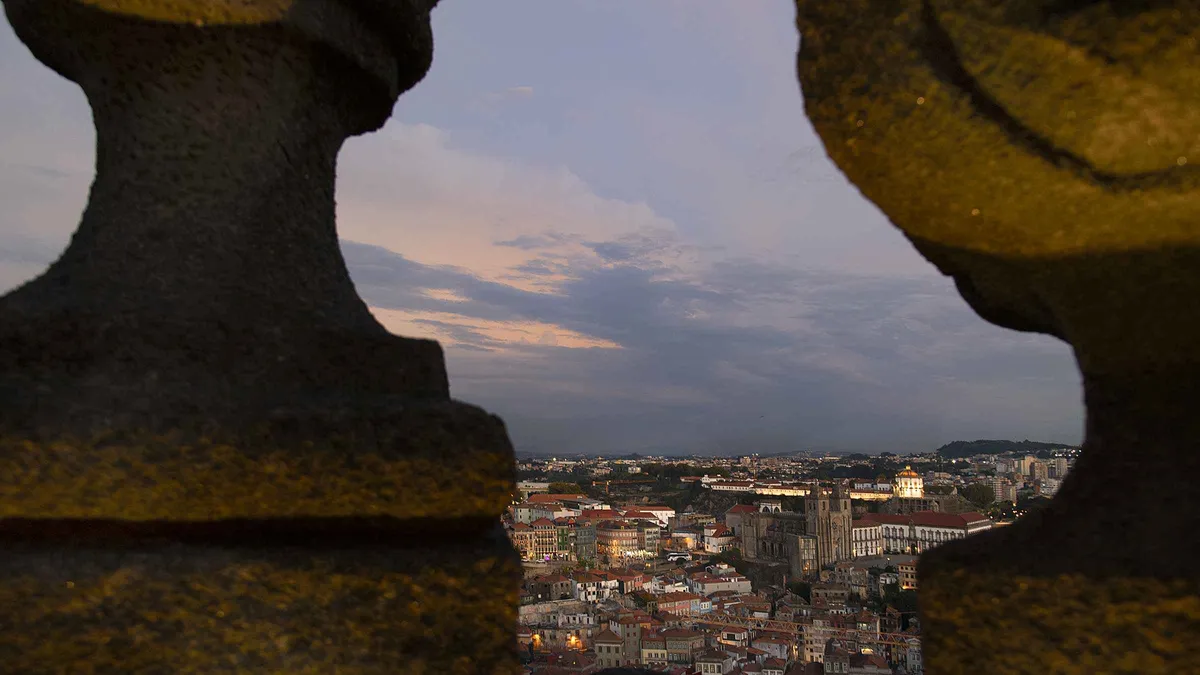 Porto's rooftops seen at dusk through an arched window of the Clérigos Tower