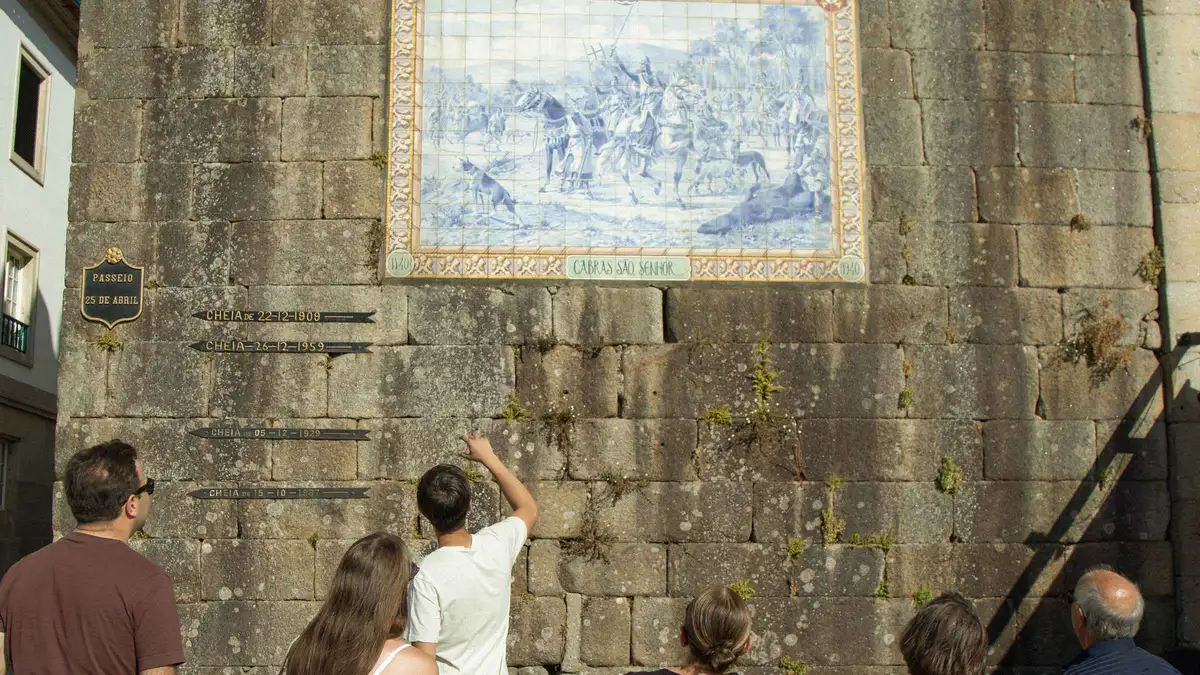 Visitors looking up at an azulejo panel on a stone wall in Ponte de Lima
