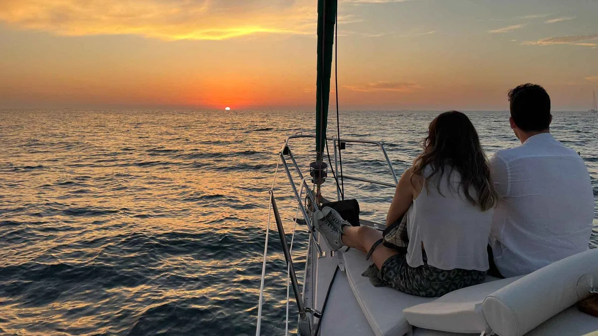 Passengers watching the sun set from the deck of a sailboat off Porto