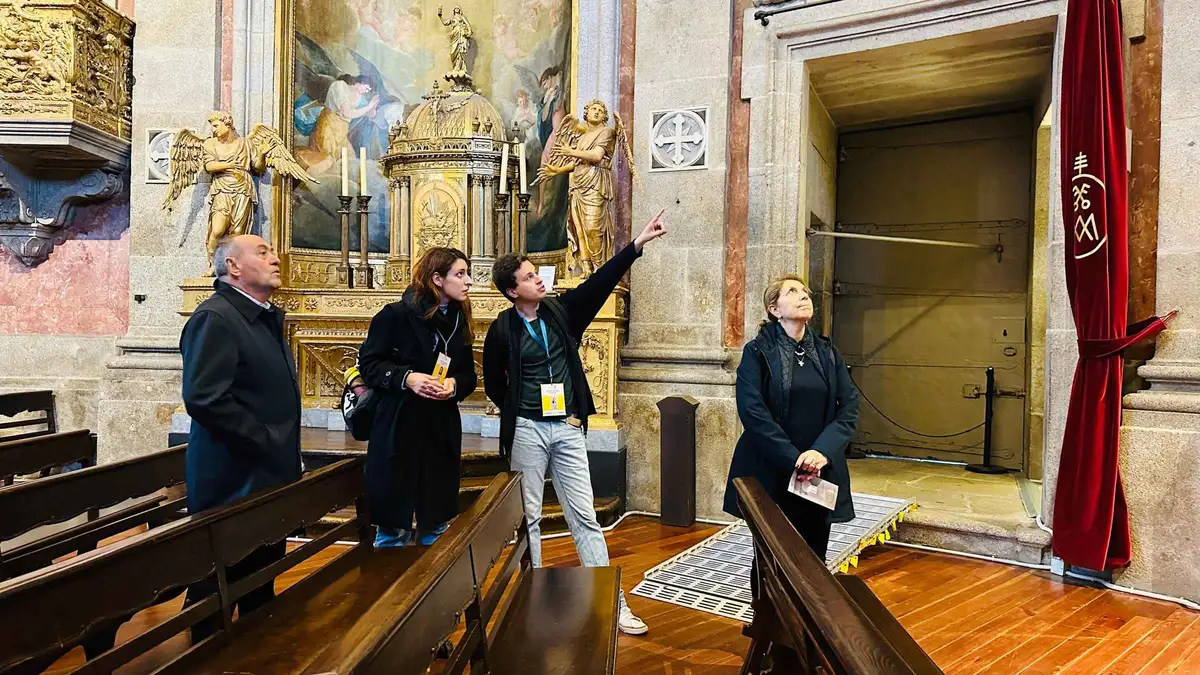 A guide pointing out gilded carvings to visitors inside a church on a Porto guided tour
