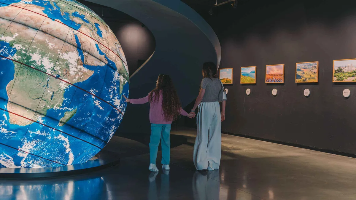 Visitors beside a giant globe inside the Wine Experience museum at WOW in Porto
