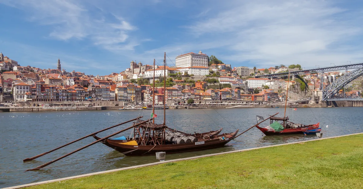 Rabelo boats moored on the Vila Nova de Gaia bank of the Douro with the Ribeira and the cathedral hill of Porto behind them
